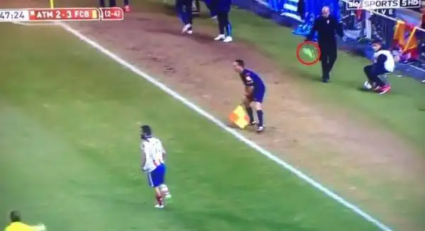 L'assistente dell'arbitro lo evita, e la scarpa sfiora un dirigente blaugrana che sta passando.
