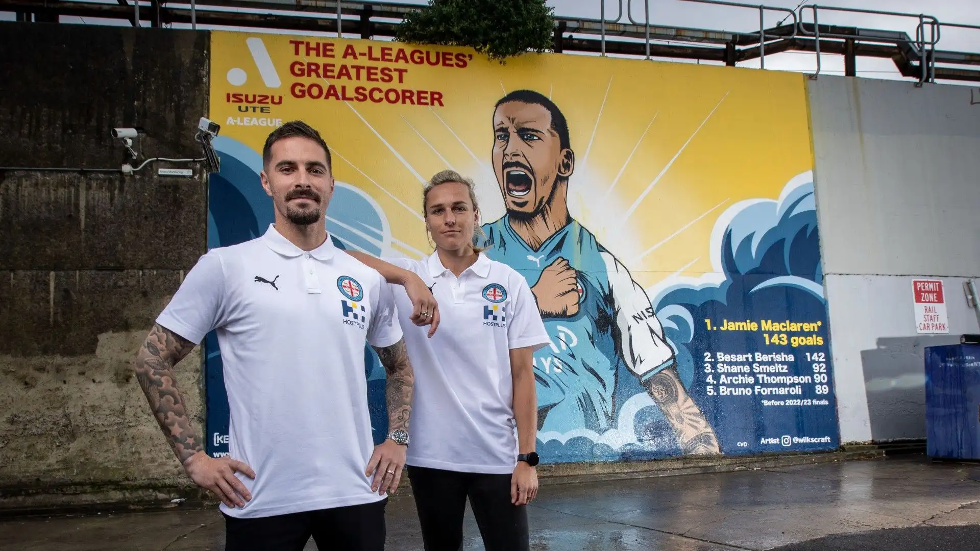 I due calciatori del Melbourne City posano davanti al murales dedicato a Jamie Maclaren