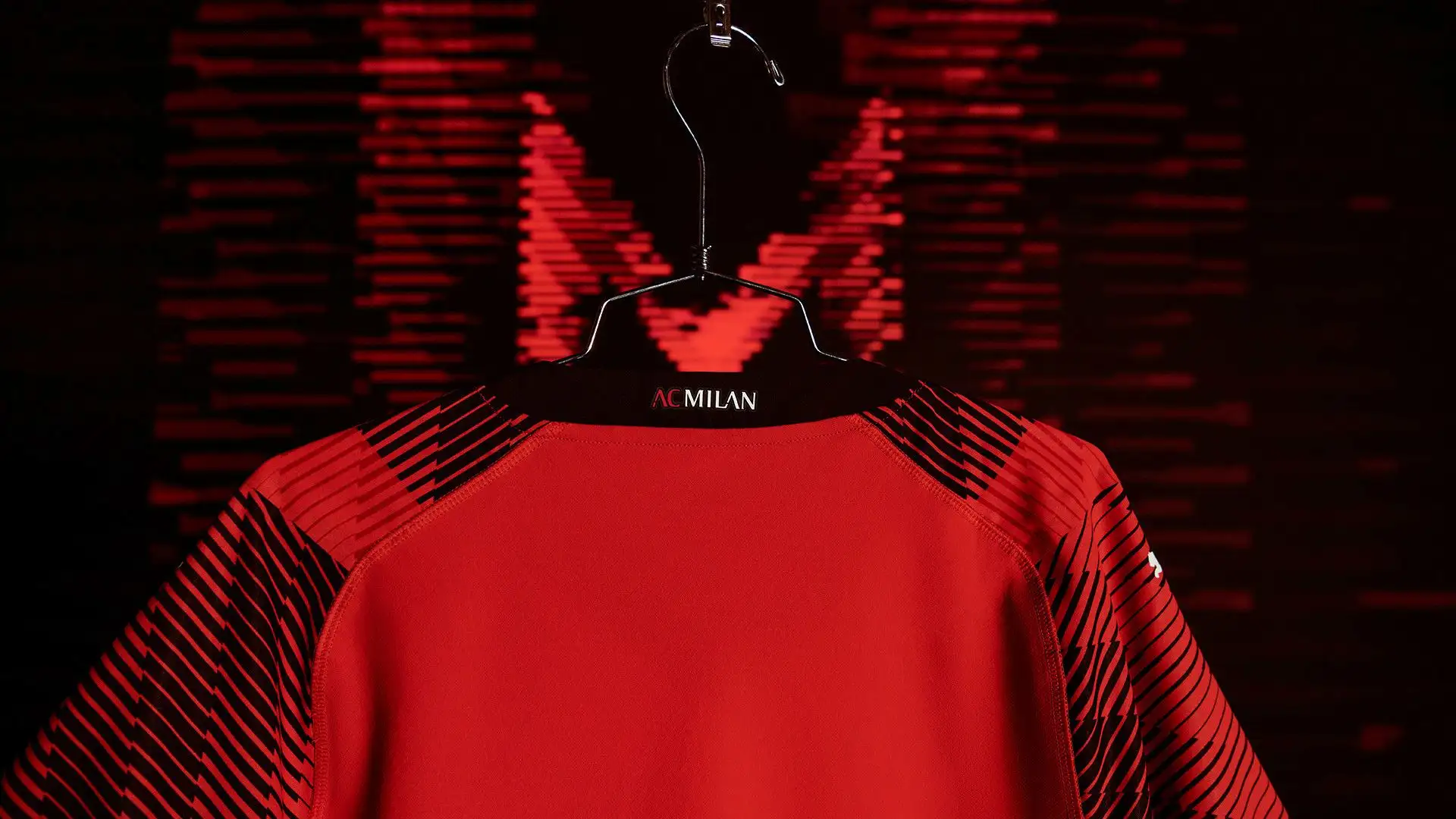 La maglia presenta un colletto nero con scollo a V e la scritta AC Milan nella parte posteriore del collo