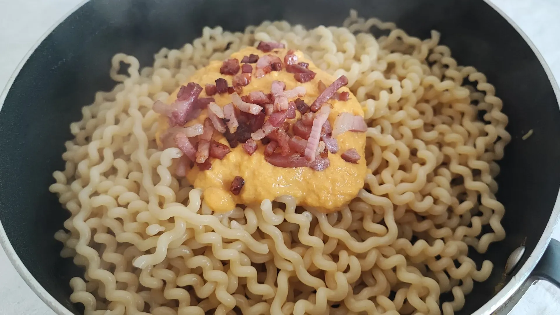 Scolate i fusilli lunghi in un tegame, versate la crema di zucca e una parte dello speck che avete rosolato. Aggiungete acqua di cottura se il composto è troppo denso

